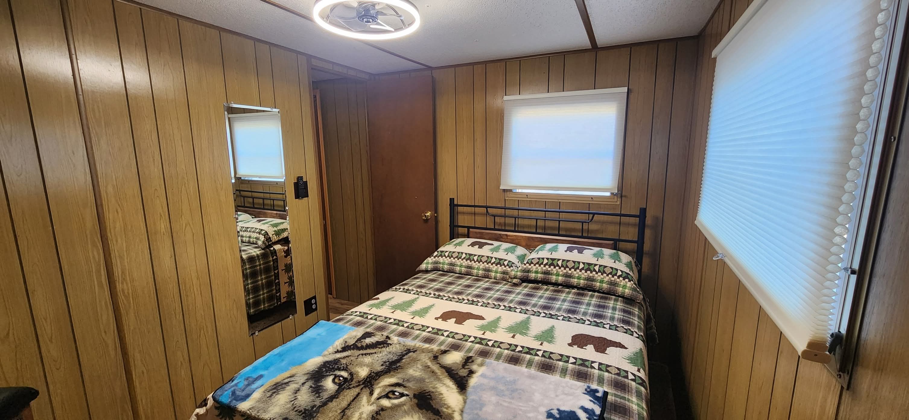 Serene second bedroom featuring a full bed dressed in soft linens, gentle bedside lamp lighting, and minimalist cabin decor, offering a quiet sanctuary for restful sleep